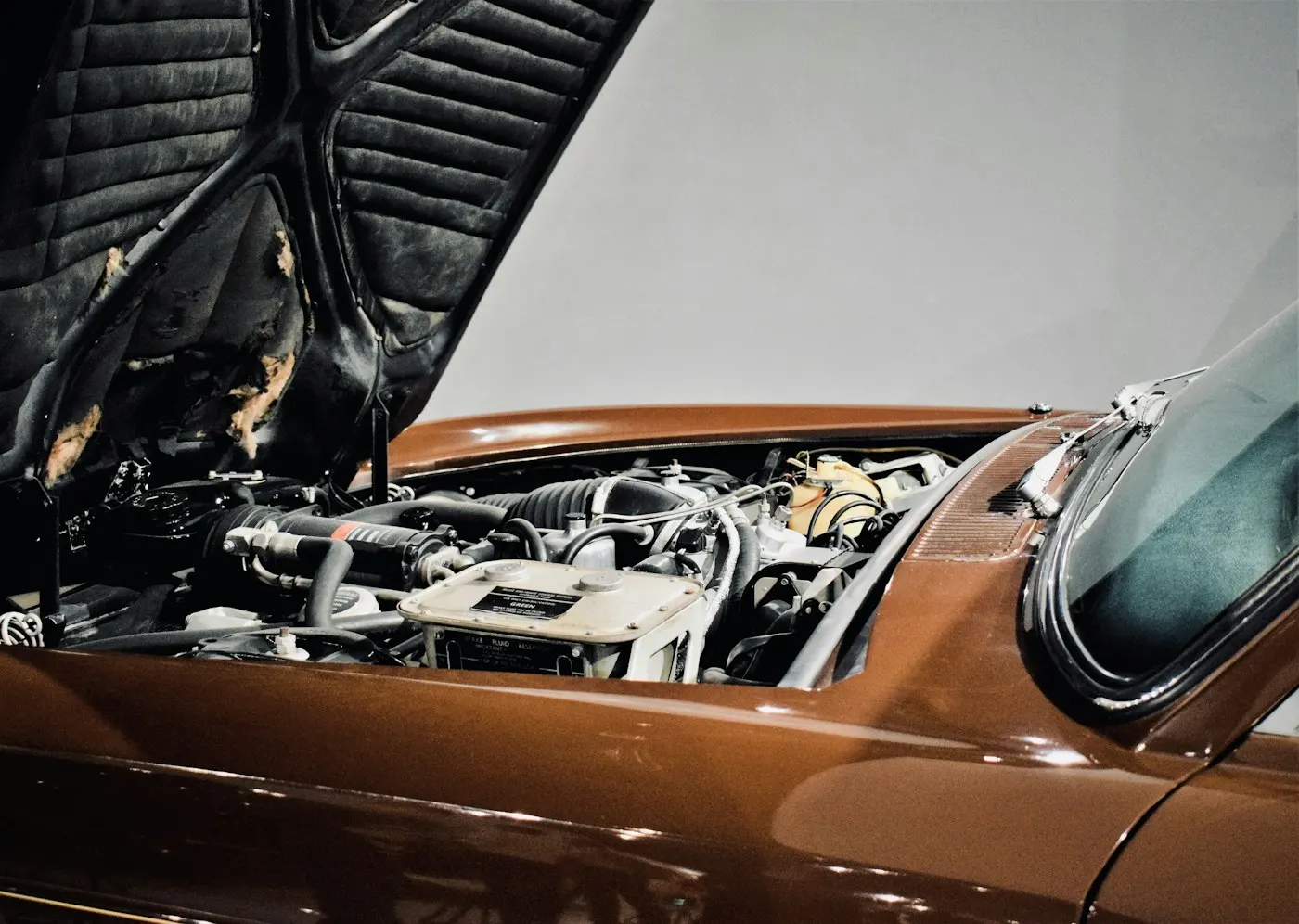 Geöffneter Motorraum eines braunen Klassikers bei der Prüfung