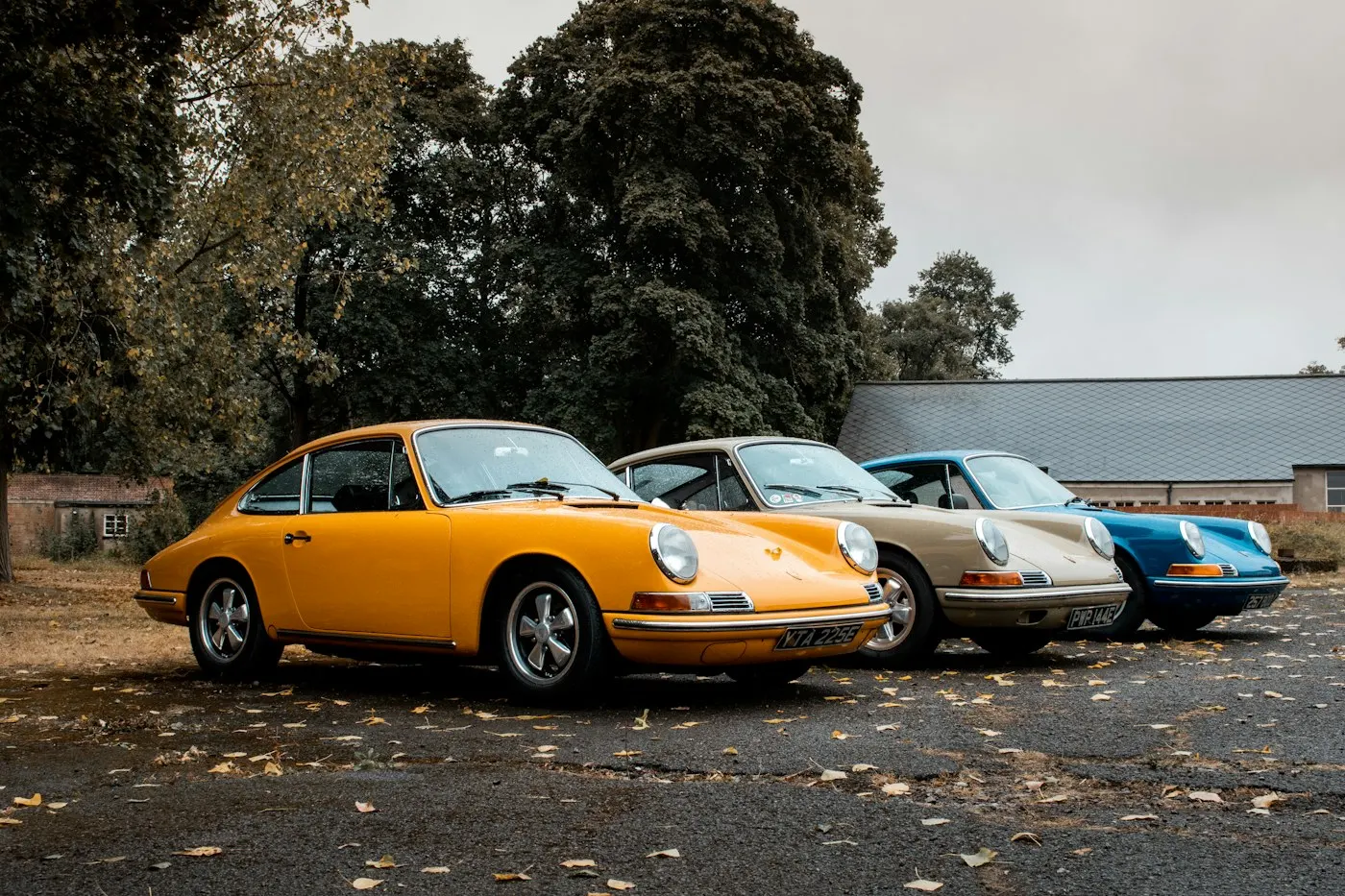 Drei klassische Porsche 911 F-Modelle in Orange, Silber und Blau nebeneinander